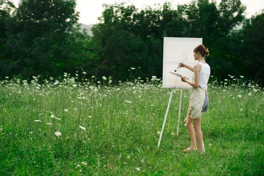 woman artist paints on easel in nature landscape. High quality photo