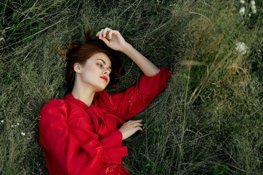 woman in red dress lies on the grass nature freedom summer. High quality photo