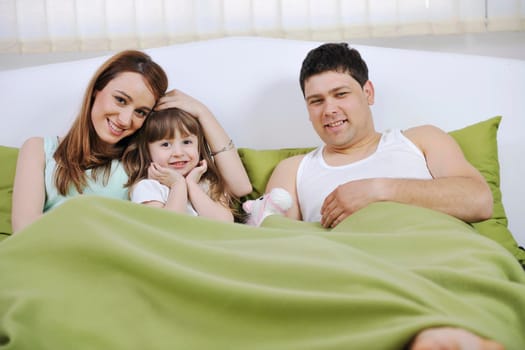 happy young family relaxing in bed 
