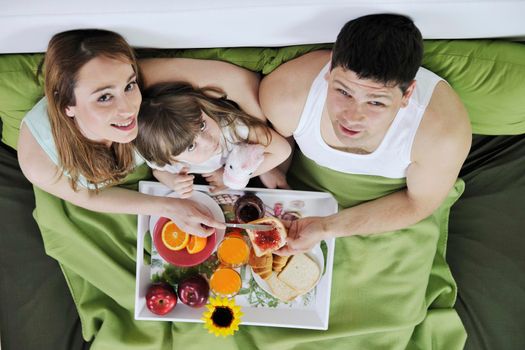 happy young family eat breakfast in bed at morning 