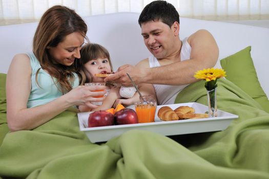 happy young family eat breakfast in bed at morning