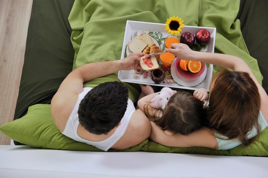 happy young family eat breakfast in bed at morning