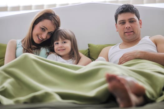 happy young family at home relaxing in bed 