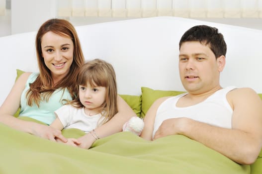 happy young family at home relaxing in bed 