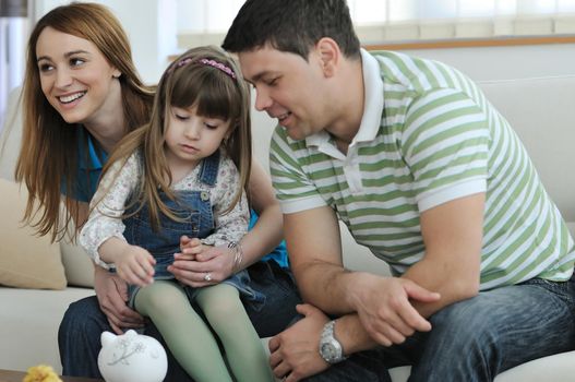 young parrent at home with beautiful child make savings and put coins money in piggy bank