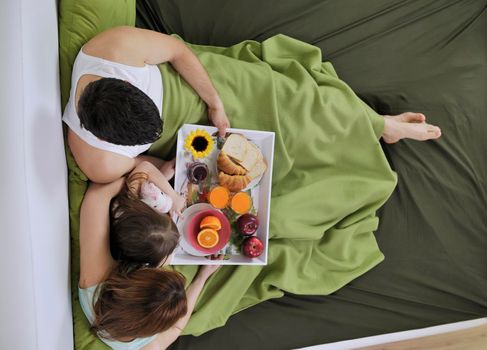 happy young family eat breakfast in bed at morning