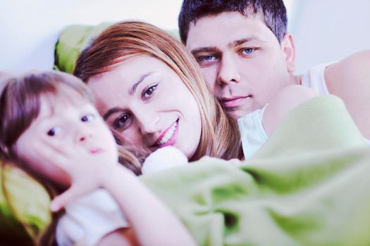 happy young family relaxing in bed 