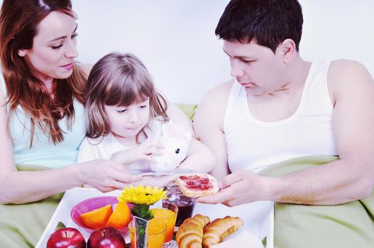 happy young family eat breakfast in bed at morning 