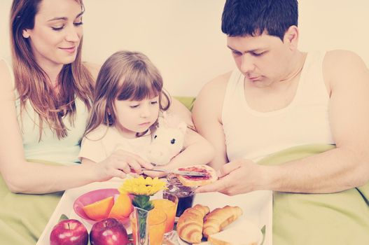 happy young family eat breakfast in bed at morning 