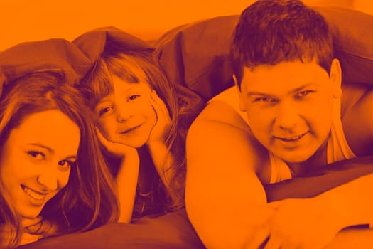 happy young family relaxing in bed duo tone