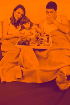 happy young family eat breakfast in bed at morning duo tone