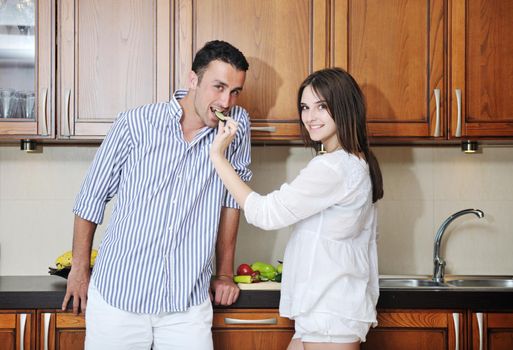 happy young couple have fun in modern wooden  kitchen indoor while preparing fresh food