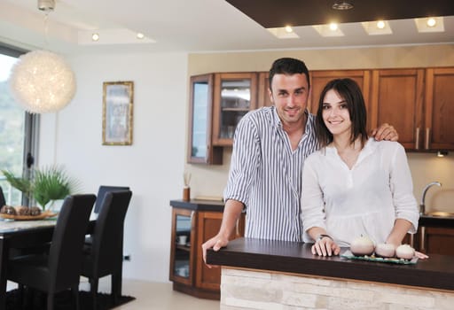happy young couple have fun in modern wooden  kitchen indoor while preparing fresh food