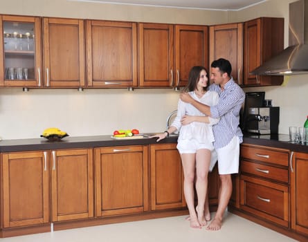 happy young couple have fun in modern wooden  kitchen indoor while preparing fresh food