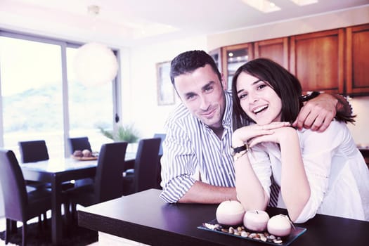 happy young couple have fun in modern wooden  kitchen indoor while preparing fresh food