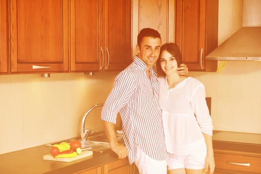 happy young couple have fun in modern wooden  kitchen indoor while preparing fresh food