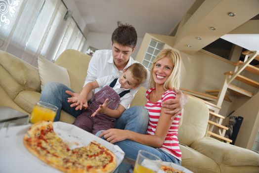 happy young family eating tasty pizza with cheesa and dring healthy and fresh orange juice