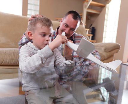 father and son assembling airplane toy at modern home living room indoor