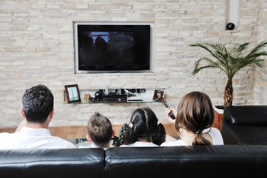 happy young family wathching flat tv at modern home indoor