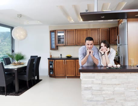 happy young couple have fun in modern wooden  kitchen indoor while preparing fresh food