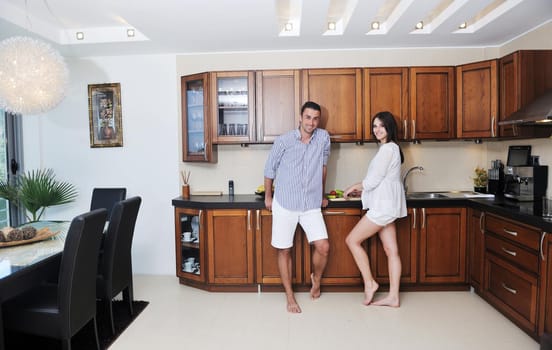 happy young couple have fun in modern wooden  kitchen indoor while preparing fresh food