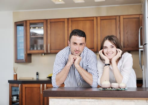 happy young couple have fun in modern wooden  kitchen indoor while preparing fresh food