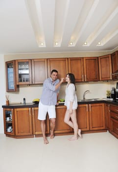 happy young couple have fun in modern wooden  kitchen indoor while preparing fresh food