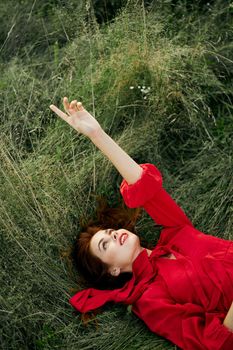 woman in red dress lies on the grass fresh air nature freedom. High quality photo