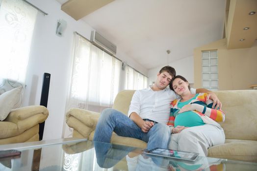 pregnant woman with her husband have fun relax and using tablet comture at modern home