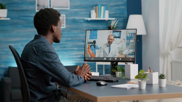 African american man with toothache seeking medical stomatologist health advice via internet video call communication. Online telehealth diagnose using webcam teethcare consultation, dental hygiene and orthodontist advice