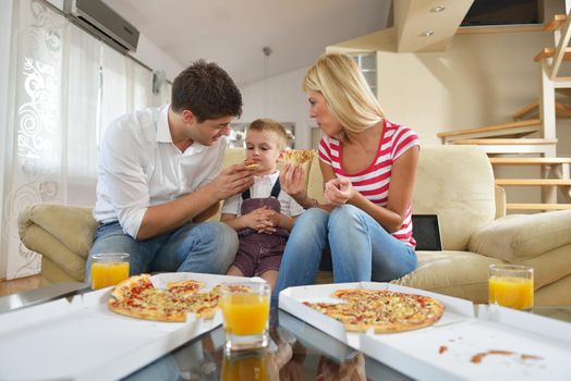 happy young family eating tasty pizza with cheesa and dring healthy and fresh orange juice