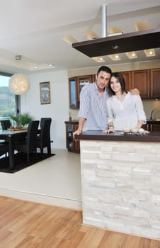 happy young couple have fun in modern wooden  kitchen indoor while preparing fresh food