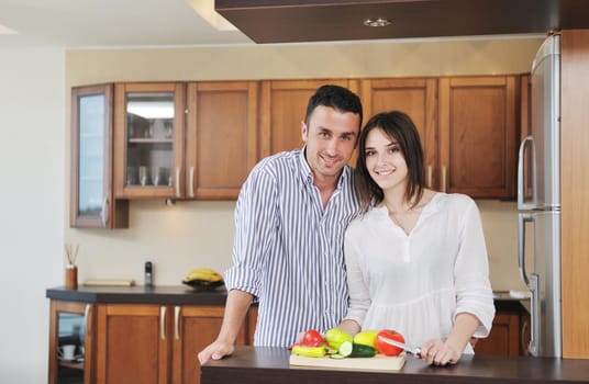 happy young couple have fun in modern wooden  kitchen indoor while preparing fresh food