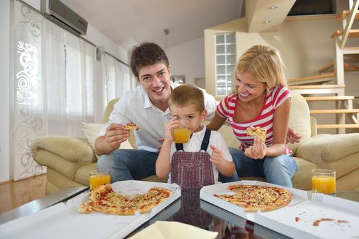 happy young family eating tasty pizza with cheesa and dring healthy and fresh orange juice