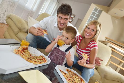 happy young family eating tasty pizza with cheesa and dring healthy and fresh orange juice