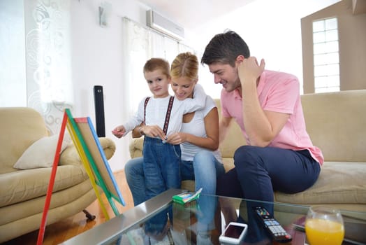 happy young family teach leassons and prepare their son for school while draw on board at home