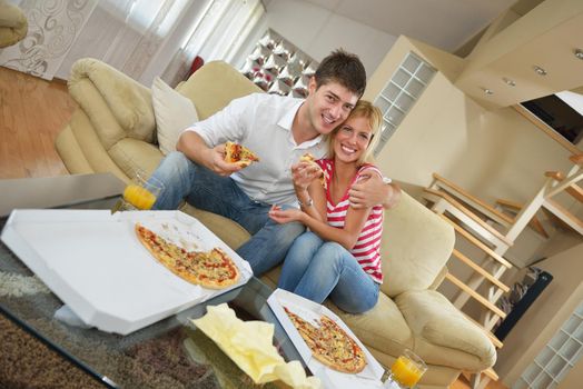 happy young couple eat fresh pizza at home relaxing and watch tv