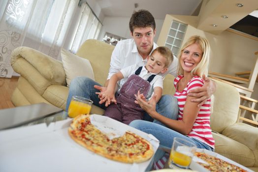 happy young family eating tasty pizza with cheesa and dring healthy and fresh orange juice