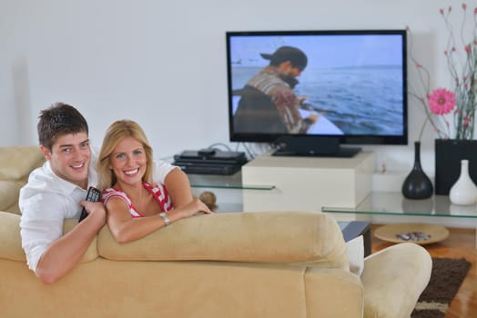 Relaxed young  couple watching tv at home in bright living room