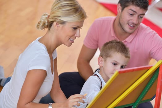 happy young family teach leassons and prepare their son for school while draw on board at home