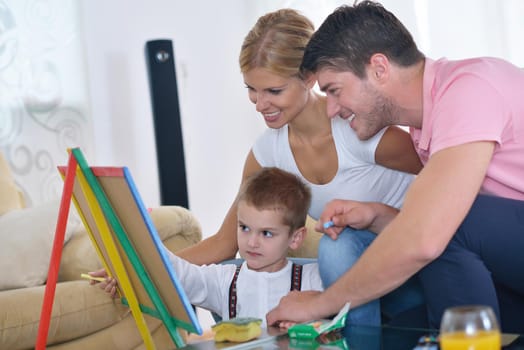 happy young family teach leassons and prepare their son for school while draw on board at home