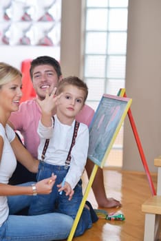 happy young family teach leassons and prepare their son for school while draw on board at home