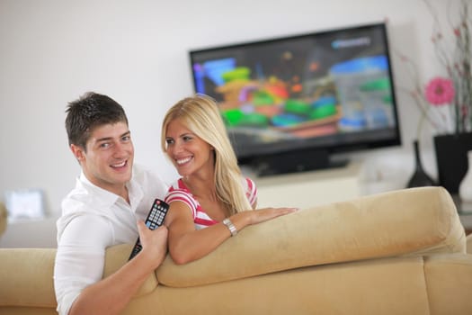 Relaxed young  couple watching tv at home in bright living room