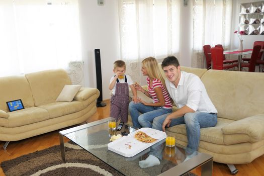 happy young family eating tasty pizza with cheesa and dring healthy and fresh orange juice