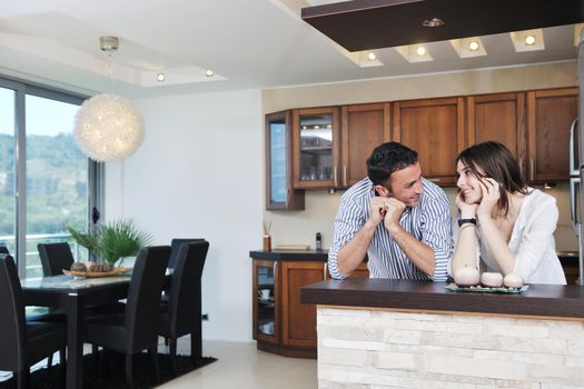 happy young couple have fun in modern wooden  kitchen indoor while preparing fresh food