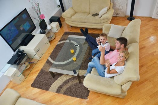 happy young family with kids in bright modern living room have fun and looking big flat lcd tv