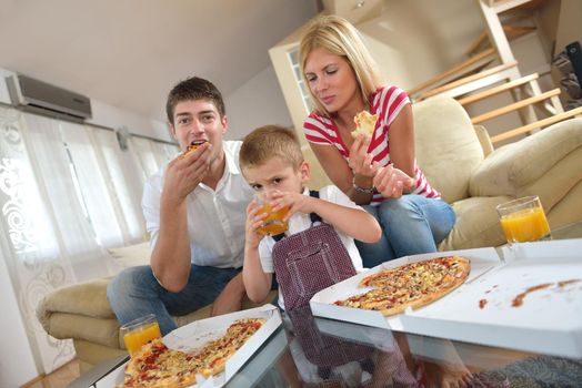 happy young family eating tasty pizza with cheesa and dring healthy and fresh orange juice