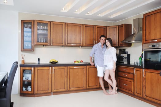 happy young couple have fun in modern wooden  kitchen indoor while preparing fresh food