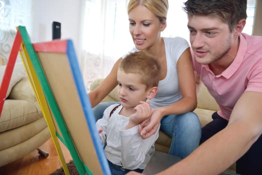 happy young family teach leassons and prepare their son for school while draw on board at home