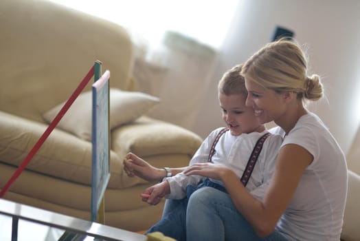 happy young family teach leassons and prepare their son for school while draw on board at home